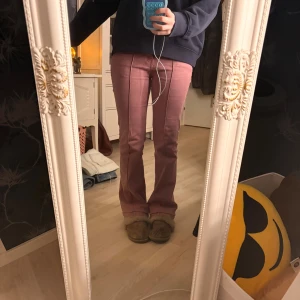 Bershka rosa bootcut jeans - Säljer ett par snygga rosa bootcut byxor med markerad söm framtill. 