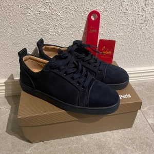 Mörkblåa Christian Louboutin mocka skor  - Snygga mörkblå sneakers från Christian Louboutin med klassisk röd sula och diskret logga på sidan. Skorna har bara använts ett par gånger.