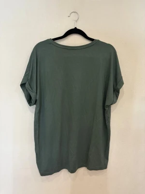 Grön loose topp från ONLY - Säljer en chill grön topp från ONLY med loose passform och korta ärmar. Toppen har rund halsringning och är gjord i mjuk bomull, perfekt för en avslappnad stil. Färgen är dovt grön och modellen är enkel utan mönster eller extra detaljer.