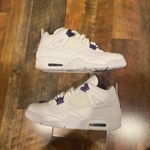 Nike Air Jordan 4s lilla vit  priset ska diskuteras storleken passar både 42 o 43 - Säljer ett par Nike Air Jordan 4 Retro med ikonisk Jumpman-logga på plösen. Skorna har snygga detaljer samt klassisk snörning och robust sula. De är inte använda mycket heller och storleken är 41.