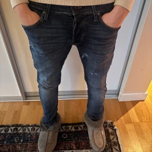 Blåa Jack & Jones 31/32 med slitningar  - Säljer ett par mörkblå jack & Jones jeans i stl 31/32 med snygga slitningar samt snygg tvätt och detaljer. Skriv vid minsta funderingar eller lägg pris förslag!