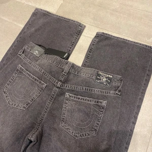 True religion jeans ”Bobby low baggy” gråa - Ett par helt nya true religion jeans som jag fick hem för ett tag sen men som tyvärr inte passade mig, därav har de inte använts. En baggy modell på jeans. Det står att dom är ”low” vilket dom blir om man låter dom vara just baggy och att dom hänger lite på höfterna!  Köpte från Nelly, nu är dom slutsålda. Jag har inga bilder med dessa jeans på mig!  •Storlek: W31  •Mått: midja: 46 cm. Innerben: 78 cm.  Benvidd:29 cm. Grenhöjd: 28 cm. Använd gärna köp nu🤩