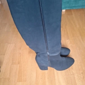 Svarta mockastövlar med klack - Snygga svarta stövlar i mocka med rund tå och stabil klack. Stövlarna har dragkedja längs sidan för enkel på- och avtagning. Perfekt höjd som ger både stil och komfort. Passar dig som vill ha en klassisk look med lite edge.