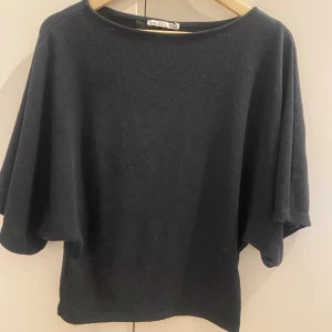Svart loose tröja - En svart tröja med lösare passform vid brösten och breda trekvartsärmar, runt halsen är den rak. Det är storlek XL men sitter mer som M