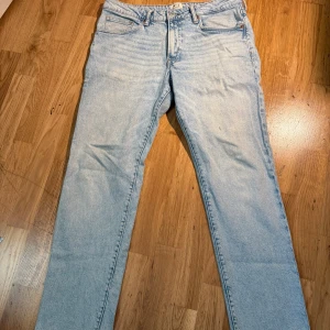 Ljusblå jeans från H&M Essentials - Säljer ett par ljusblå regular fit jeans från H&M Essentials, modell No 2. Klassisk femficksdesign med raka ben och normal passform. Materialet är 99% bomull och 1% elastan för lite stretch. Perfekt för dig som gillar enkel och clean denimstil.
