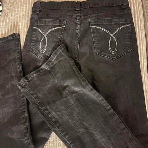 Svarta bootcut jeans från Calvin Klein - Svarta jeans från Calvin Klein med bootcut passform och snygga kontrastsömmar på bakfickorna. Klassisk femficksmodell med knapp och dragkedja fram. Jeansen är tillverkade i mjukt denimtyg och har en stilren look med diskret logga på fickan.