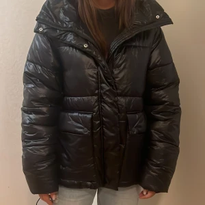 Pufferjacka indiska  - Svart pufferjacka från Indiska. Aldrig använd då jag köpt en annnan vinterjacka . Huva medföljs. Prislapp kvar . Nypris: 1059 kr