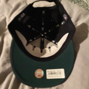 New era keps - Snygg svart keps från New Era med White Sox-logga i vitt framtill och MLB-märke bak. Modellen är 9Fifty med justerbar rem i metall. Skärmen är mörkgrön undertill och kepsen är tillverkad i bomull. Perfekt för dig som gillar sportig streetstyle. Helt ny, glömde skicka tillbaks.