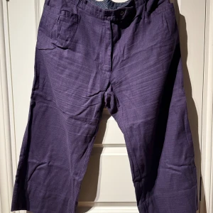 Lila byxor från Gudrun Sjödén XL - Snygga lila byxor från Gudrun Sjödén i storlek XL. Byxorna har en rak och lite loose passform med klassisk midja och praktiska fickor framtill. Materialet känns mjukt och bekvämt, perfekt för dig som gillar färg och stil.