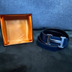 Navy och Silvrigt H-bälte - Navy skärp med silvrigt H. 110cm. Använt fåtal gånger. Lådan följer med! Skick 9/10🌟Pris kan diskutera🙌🏻 Hör av dig vid funderingar!