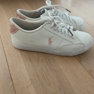 Vita Polo Ralph Lauren sneakers med glitter - Snygga vita sneakers med rosa glitter. Storlek 39. Bara använda några gånger. Pris går att diskutera. 