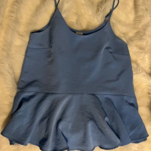 Blå volang topp - Jättefin blå volang topp i storlek 10, ungefär M-L. Den är från märket river Island och är i bra skick. Bara att fråga om fler bilder ifall det behövs!