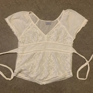 Vit broderad blus från Oasis - Söt vit blus från Oasis med broderade blommor, v-ringning och knytband i midjan. Blusen har korta ärmar med spetskant och fina detaljer längs sömmarna. Perfekt till jeans eller kjol för en romantisk look. Passar mig som brukar ha stl xs💕