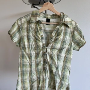 Grön- och vitrutig skjorta Vero Moda - Supersöt kortärmad skjorta från Vero Moda i grönt, vitt och inslag av gult. Skjortan har klassisk krage, knappar framtill och ett rutigt mönster. Skriv gärna för fler bilder och vid frågor, köparen står för frakt. Pris kan diskuteras! 💕