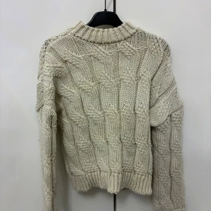 Beige stickad tröja från NA-KD - Säljer en chunky beige stickad tröja från NA-KD i storlek XXS/XS, passar även dig som har storlek S.. Tröjan har ett grovt kabelstickat mönster, ribbade muddar och hög hals. Perfekt för lager-på-lager och en mysig vibe under kyliga dagar. Aldrig använd.