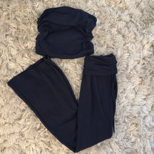 Mörkblått set från SHEIN - Säljer ett par mörkblå bootcut byxor och en tillhörande topp från SHEIN i ribbat material. Byxorna har låg midja med knytband och vida ben. Perfekta för dig som gillar en trendig och bekväm stil. Materialet är mjukt och stretchigt, vilket gör dem riktigt sköna att bära.