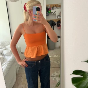 Orange linnetopp med volang och rosett - Superfin orange linnetopp med smala axelband, volang nertill och stor rosett i ryggen. 