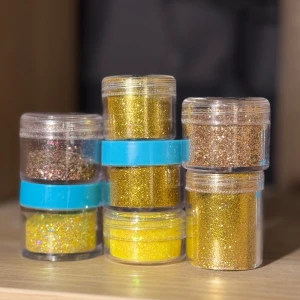 7 pack glitter till naglar  - 7 burkar med löst glitter i nyanser av guld. Kommer i små genomskinliga plastburkar. Burken till vänster är halvfullt! Burkarna kan ha repor pga att ha legat bland andra produkter och märkta med något nummer, men det är inga problem med produkterna. 