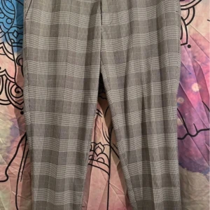 Rutig super skinny byxa från ASOS - Grå och vitrutiga kostymbyxor från ASOS DESIGN i super skinny-modell. Byxorna har hög stretch och sitter tight hela vägen ner. Materialet är en mix av polyester, viskos och elastan för en mjuk och följsam känsla. Perfekt för dig som gillar en modern och stilren look.