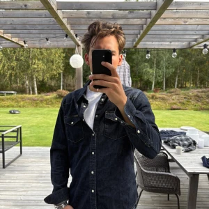 Mörkblå jeansskjorta från Lee - Snygg mörkblå jeansskjorta från Lee med klassisk krage och vita knappar. Skjortan har två bröstfickor med lock och kontrastsömmar som ger en cool look. Perfekt att bära öppen över en t-shirt eller stängd för en mer stilren vibe.