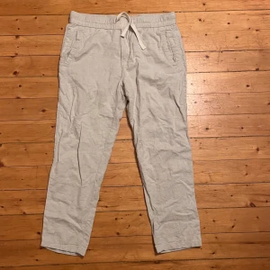 Ljusbeige linnebyxor från Zara - Snygga ljusbeige linnebyxor från Zara med avslappnad passform och elastisk midja med snörning. Byxorna har sidofickor och en bakficka, perfekta för chill dagar. Materialet är linne som ger en skön och luftig känsla. Passar dig som gillar stilren och enkel look.