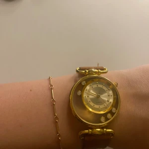 Guldig klocka med brunt läderband - Mycket snygg klocka med läderband, batteri funkar ej och måste bytas (ingår ej)