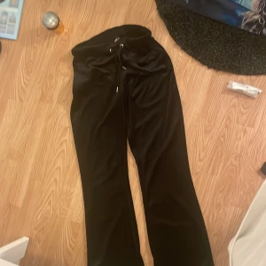 Svarta mjukisbyxor med snörning - Svarta mjukisbyxor i mjukt material med breda ben och snörning i midjan. Perfekta för en chill och avslappnad stil. Snygg passform och sköna att ha på sig hela dagen.