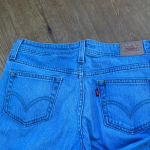 Levi's 518 Superlow Bootcut Jeans - Snygga ljusblå Levi's 518 Superlow jeans med bootcut. Klassisk femficksmodell med låg midja och ikoniska Levi's-detaljer som röd logotag på bakfickan. Tillverkade i mjuk bomullsdenim, perfekta för en avslappnad och cool look.