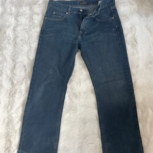 Blå jeans från 8STIN med raka ben - Snygga blå jeans från 8STIN med raka ben och klassisk femficksdesign. Jeansen har ljusa kontrastsömmar, unika bakfickor med broderad detalj och råa, fransiga benslut för en avslappnad vibe. Perfekta till sneakers eller boots.