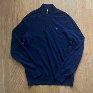 Mörkblå merinoullströja från Morris - Säljer en mörkblå långärmad tröja från Morris i 100% merinoull. Tröjan har hög krage med half zip-dragkedja och en liten broderad logga på bröstet. Storleken är M men passar S. Perfekt för dig som gillar stilrena och bekväma plagg med premiumkänsla.