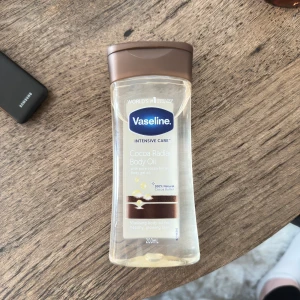 Vaseline Cocoa Radiant Body Oil - Vaseline Intensive Care Cocoa Radiant Body Oil med 100% naturlig kakaosmör. Oljan är genomskinlig och kommer i en plastflaska med brunt lock, 200 ml. Perfekt för att ge huden en glowig finish och extra fukt. ENDAST TESTAD 
