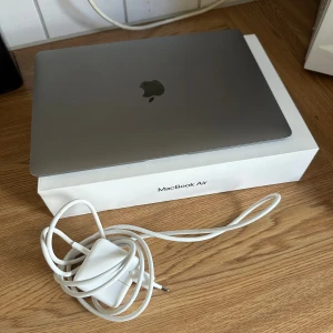 MacBook Air 13-inch - Apple MacBook Air 13-tum med originalkartong och laddare. Datorn fungerar men har synliga skador vid gångjärnet på skärmen (se bild 3). Tangentbord och skärm i övrigt i gott skick, nedåtpil kan fastna ibland. Perfekt för studier eller arbete. Säljes i befintligt skick.