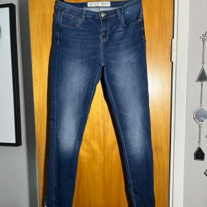 Mörkblå skinny jeans  - Snygga mörkblå skinny jeans med klassisk femficksdesign och smal passform. Jeansen har hög midja och är tillverkade i stretchigt denim för en bekväm känsla. Perfekt för dig som gillar en tajt siluett och stilrena detaljer.