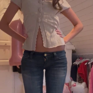 Baby doll  big button sktickad kofta beige spets 🪽🫖 - Supersöt beige blus med korta ärmar och stora dekorativa knappar framtill. Blusen har v-ringning, vågig kant längs knäppningen och är lätt utsvängd nertill. Perfekt för dig som gillar en feminin och trendig stil. Spets på kanterna. Köpt på Vinted.