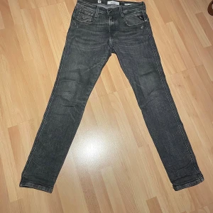 Replay Anbass svarta slim jeans - Snygga svarta Replay Anbass jeans i slim fit med klassisk femficksdesign. Jeansen har en något tvättad look och smal passform som sitter slim längs benen. Perfekta för dig som gillar en modern och stilren stil.