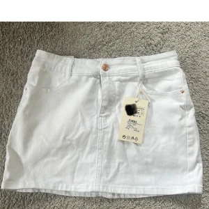 Vit jeanskjol från Missay - Snygg vit jeanskjol från Missay med klassisk femficksdesign, bälteshällor och knappstängning framtill. 