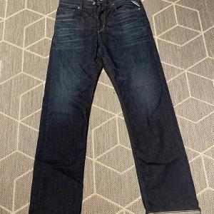 Mörkblå Replay jeans straight fit - Snygga mörkblå jeans från Replay med klassisk femficksdesign och raka ben. Jeansen har tydliga kontrastsömmar, läderpatch bak och Replay-logga vid fickan. Tillverkade i slitstarkt denim för en tidlös look. Är  aldrig använd!!