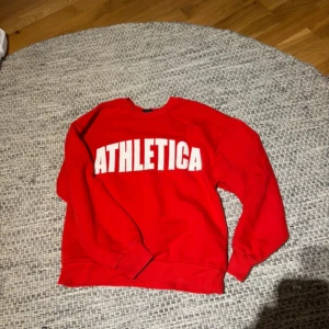 Röd sweatshirt ATHLETICA Gina Tricot - Röd sweatshirt från Gina Tricot med stor vit ATHLETICA-text framtill. Klassisk rund halsringning och långa ärmar med ribbade muddar. Perfekt för en sportig look och chill dagar. Mjuk insida och relaxed fit. Är i storlek xxs men passar mig som har xs, väldigt bra skick