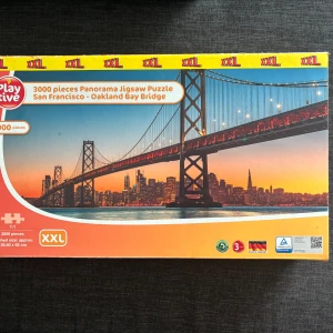 Pussel - Stort panoramapussel med 3000 bitar, motiv av Oakland Bay Bridge i San Francisco. Pusslet är i XXL-format och levereras komplett i originalkartong. 