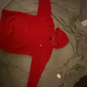 Röd Jordan hoodie med huva - Säljer en snygg röd hoodie från Jordan med klassisk logga på bröstet. Tröjan har huva, magficka och är tillverkad i mjukt bomullsmaterial. Perfekt för dig som gillar streetwear och sportig stil.