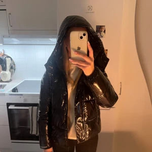 Svart pufferjacka från Calvin Klein - Säljer en svart, glansig pufferjacka från Calvin Klein Jeans med huva och dragkedja. Jackan har quiltad design, långärmad passform och logga på bröstet samt ärmslutet. Perfekt för kalla dagar och har en riktigt snygg street vibe. Har däremot en liten reva på vänster arm men går att laga hur lätt som helst!!                                                                   Köptes för 2300kr säljer då den inte kommer till användning, pris går att diskutera!!