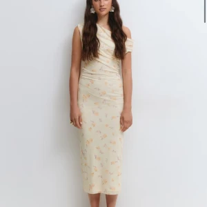 Ljus blommig omlottklänning NY MED LAPP GINATRICOT - Nypris 500! ✨ Säljer en ljus, axelbandslös omlottklänning med blommigt mönster i mjuka pastellfärger. Klänningen har en oneshoulder-design och är figurnära med draperade detaljer. Perfekt för dig som gillar romantisk och feminin stil.