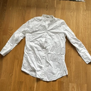 Vit henley-skjorta från Esprit - Klassisk vit henley-skjorta från Esprit i bomull. Skjortan har lång ärm, ståkrage och knappar framtill. Perfekt för en clean och stilren look. Passar dig som gillar enkel och tidlös stil.