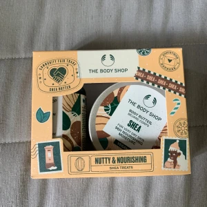 The Body Shop Shea Treats Kit - Ett presentkit från The Body Shop med shea body butter och duschkräm. Innehåller en rund burk med body butter (50 ml) och en tub med duschkräm (60 ml), båda med närande sheasmör. Förpackningen är beige med gröna och bruna detaljer och illustrationer. Aldrig använd då jag fick den i present för ett par år sedan. 