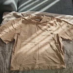 Beige basic t-shirt i bomull - Enkel och stilren beige t-shirt i mjuk bomull. Klassisk passform med rund hals och korta ärmar. 