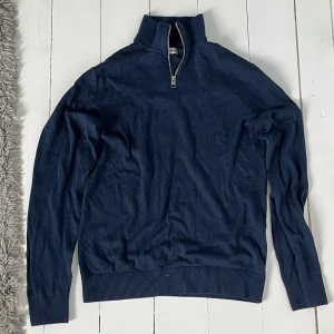 Mörkblå half zip tröja Jack & Jones - Mörkblå långärmad tröja från Jack & Jones med half zip och hög krage. Tröjan är ribbad vid ärmslut och nederkant, perfekt för dig som gillar en stilren och enkel look. Materialet är mjukt och passar bra till lager-på-lager.