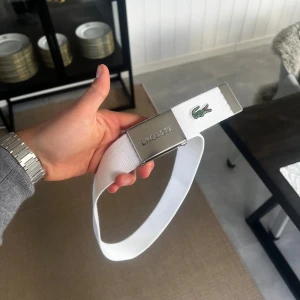 Lacoste Bälte, 10-14 år, Vitt, Mycket Bra Skick - Hej! Säljer nu det här Lacoste bältet då det är för litet och inte kommit till användning. Bältet är gjort av tyg, använd ett fåtal gånger och i mycket bra skick. Justerbart för perfekt passform.  Storlek: 10-14år Färg: Vitt  Kan skickas (köparen står för frakt) eller hämtas i Täby. Först till kvarn gäller.  Vid frågor eller för fler bilder - skicka gärna ett meddelande.  Mvh William