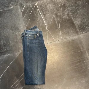 Slim Glenn blå jeans storlek 30/32 - Snygga blå jeans från Slim Glenn i storlek 30/32. Modellen har en slim passform med klassisk femficksdesign och gul kontrastsöm. Jeansen är raka och har en modern look som funkar till sneakers eller boots. Materialet är slitstarkt denim. Pris kan diskuteras 
