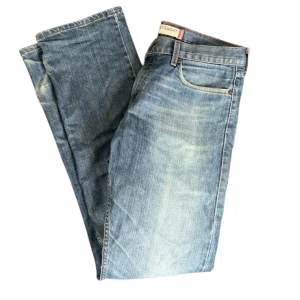 Levi's 514 Slim Straight jeans blå - Snygga Levi's 514 Slim Straight jeans i klassisk blå tvätt med slitningar. Modellen har fem fickor, normal passform och raka ben. Perfekt för dig som gillar en tidlös look med lite edge.