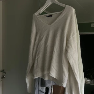 Vit stickad v-ringad tröja - Mysig vit stickad tröja från Lager 157 med v-ringning och avslappnad passform. Tröjan har långa ärmar och ribbade muddar, perfekt för lager-på-lager under kyliga dagar. Enkel att styla till jeans eller kjol nu till hösten och vintern